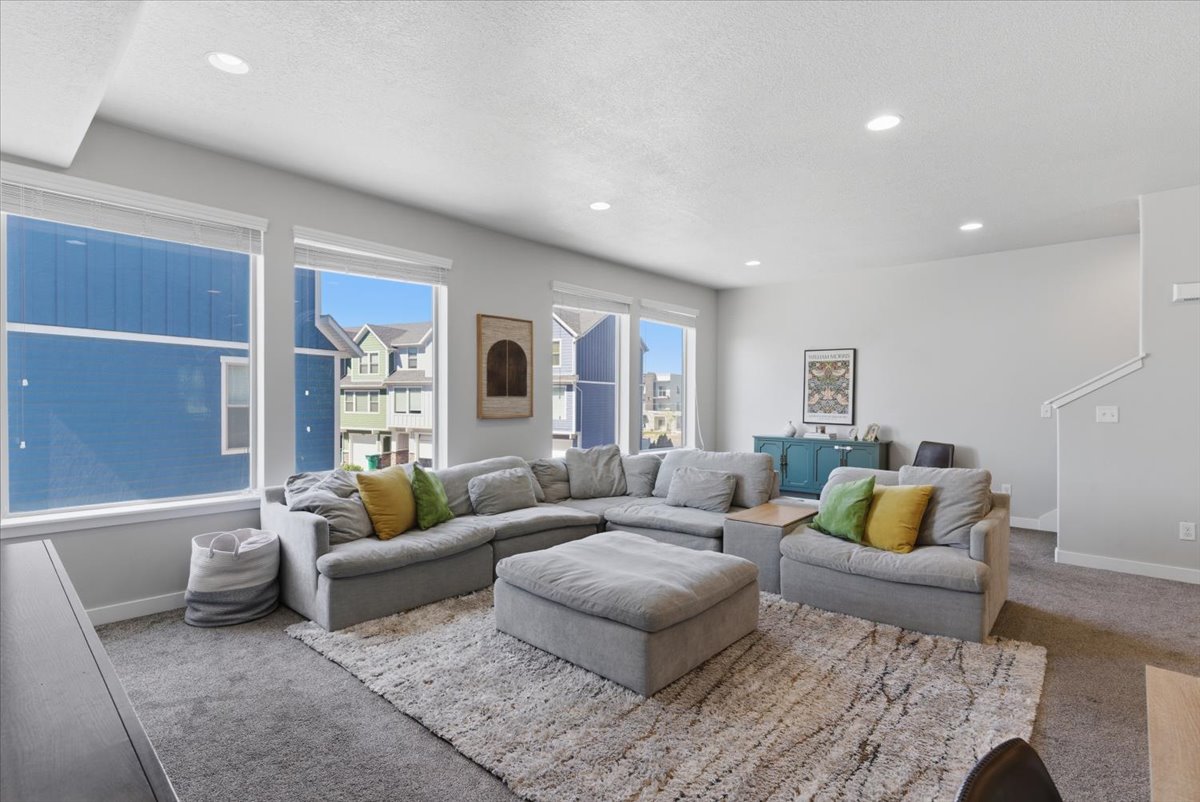 Bright living area featuring recessed lighting, a neutral color palette, multiple large windows, and carpet flooring