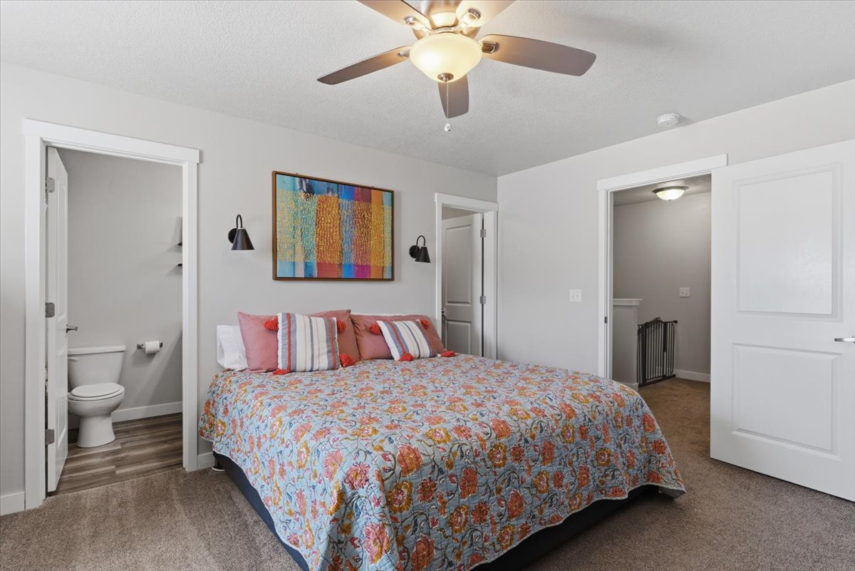 Carpeted room featuring a ceiling fan with integrated lighting, wall-mounted sconces, and a white paneled door