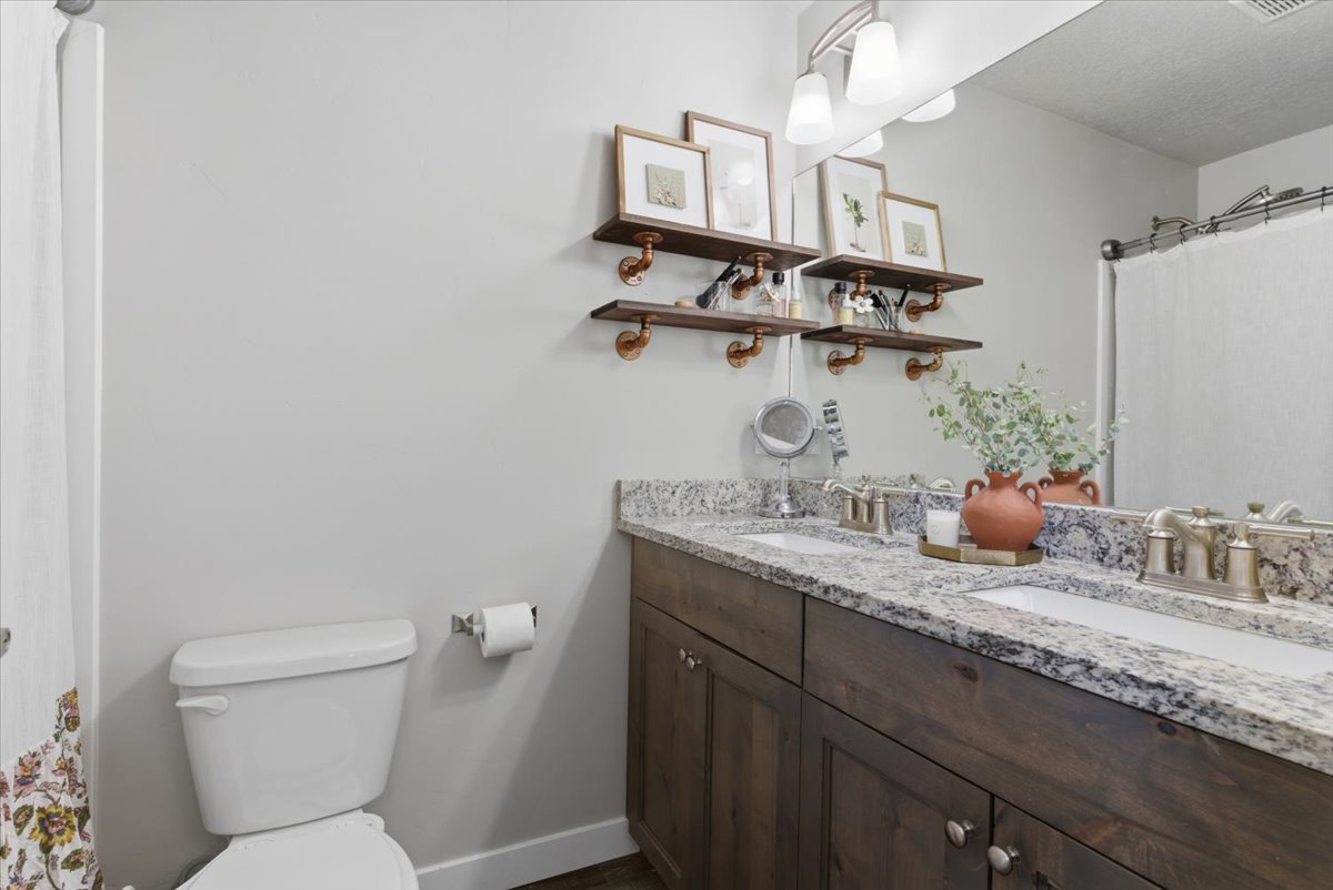 Double vanity featuring a granite countertop with two integrated sinks and brushed nickel faucets