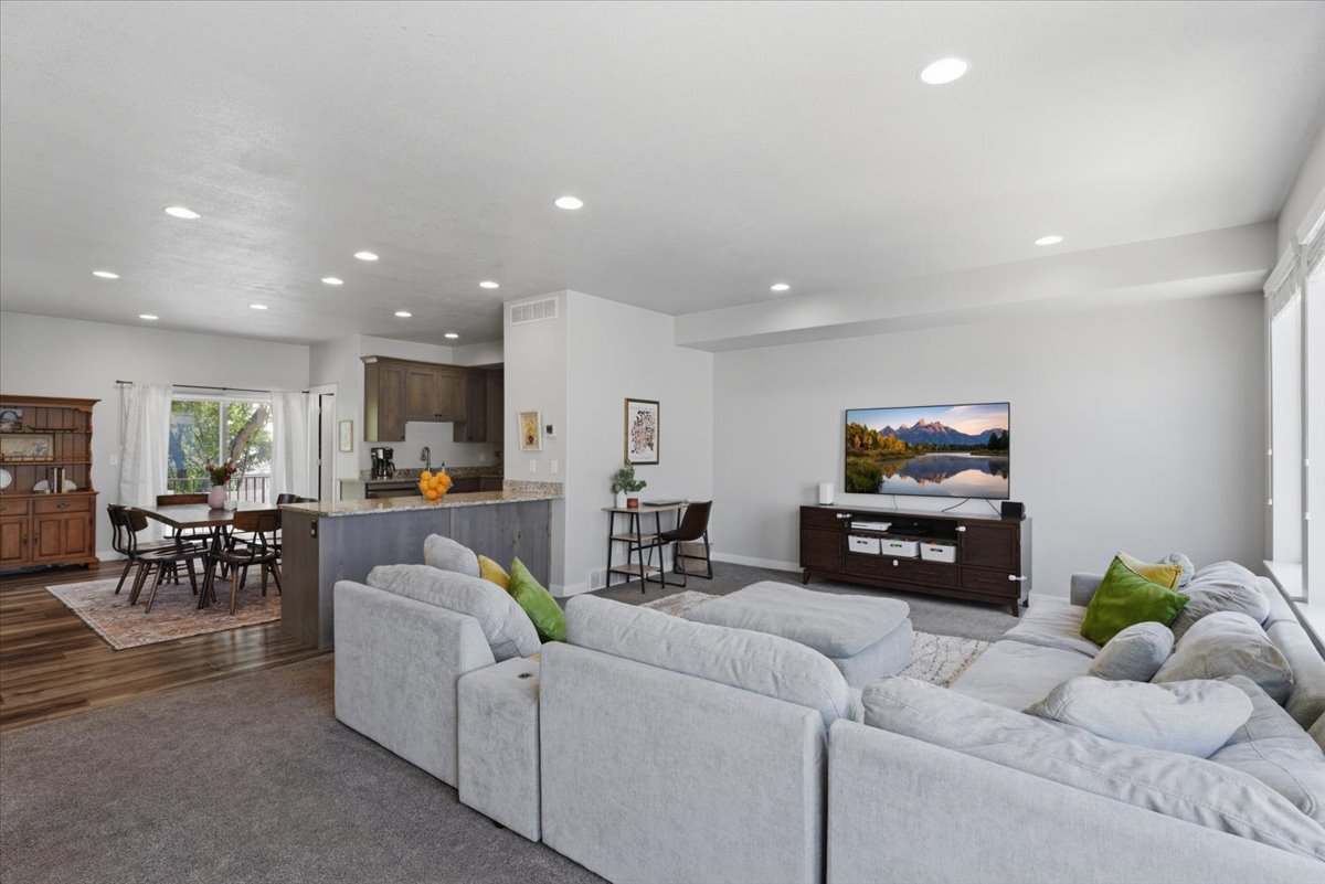 Open-concept living area with recessed lighting, light gray wall color, and a large window providing natural illumination