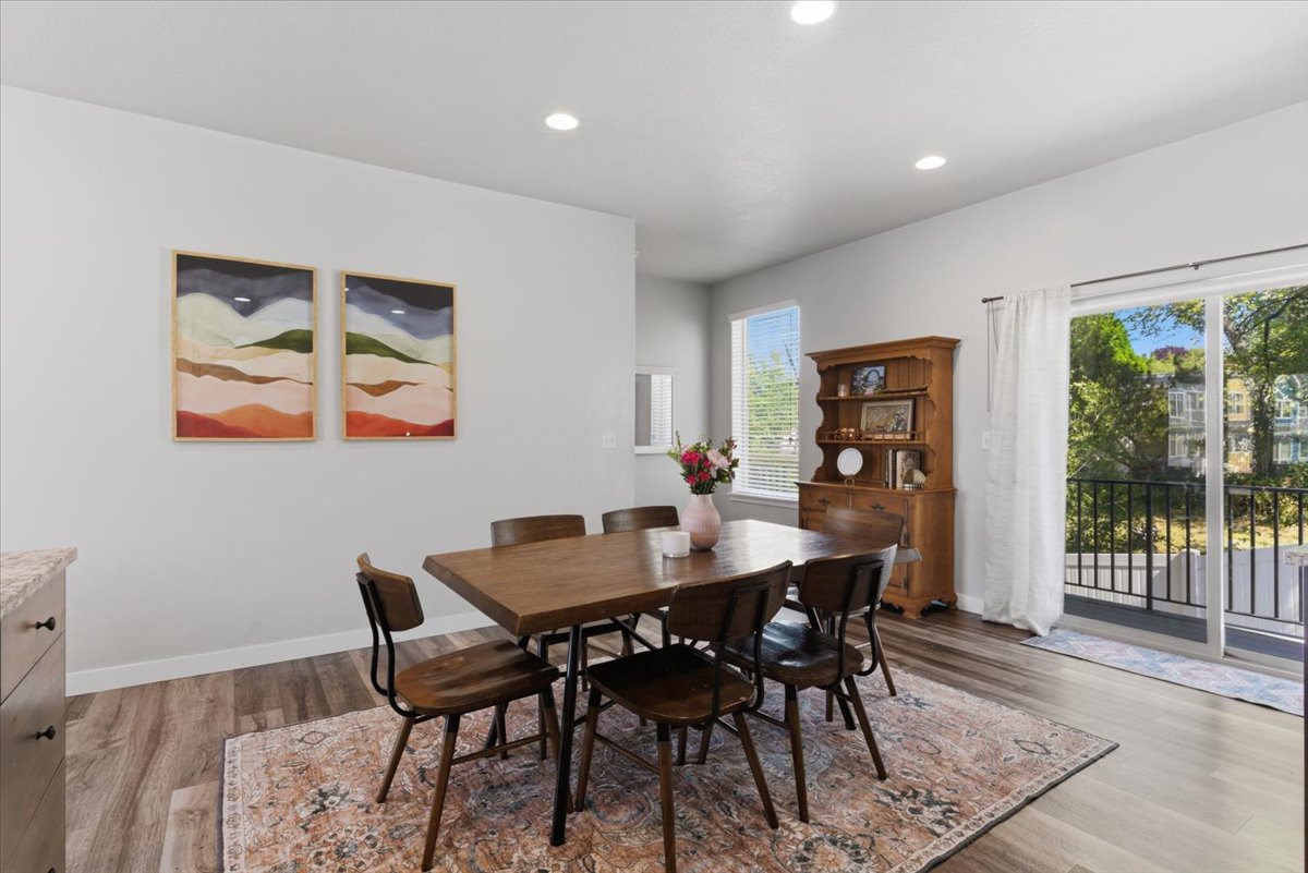 Dining area featuring wood-finish flooring, recessed lighting, and a sliding glass door leading to a balcony with black metal railing