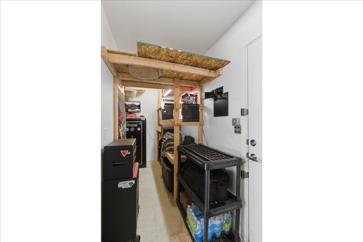 Dedicated storage area featuring built-in wooden shelving, a white interior door, and a light-colored floor