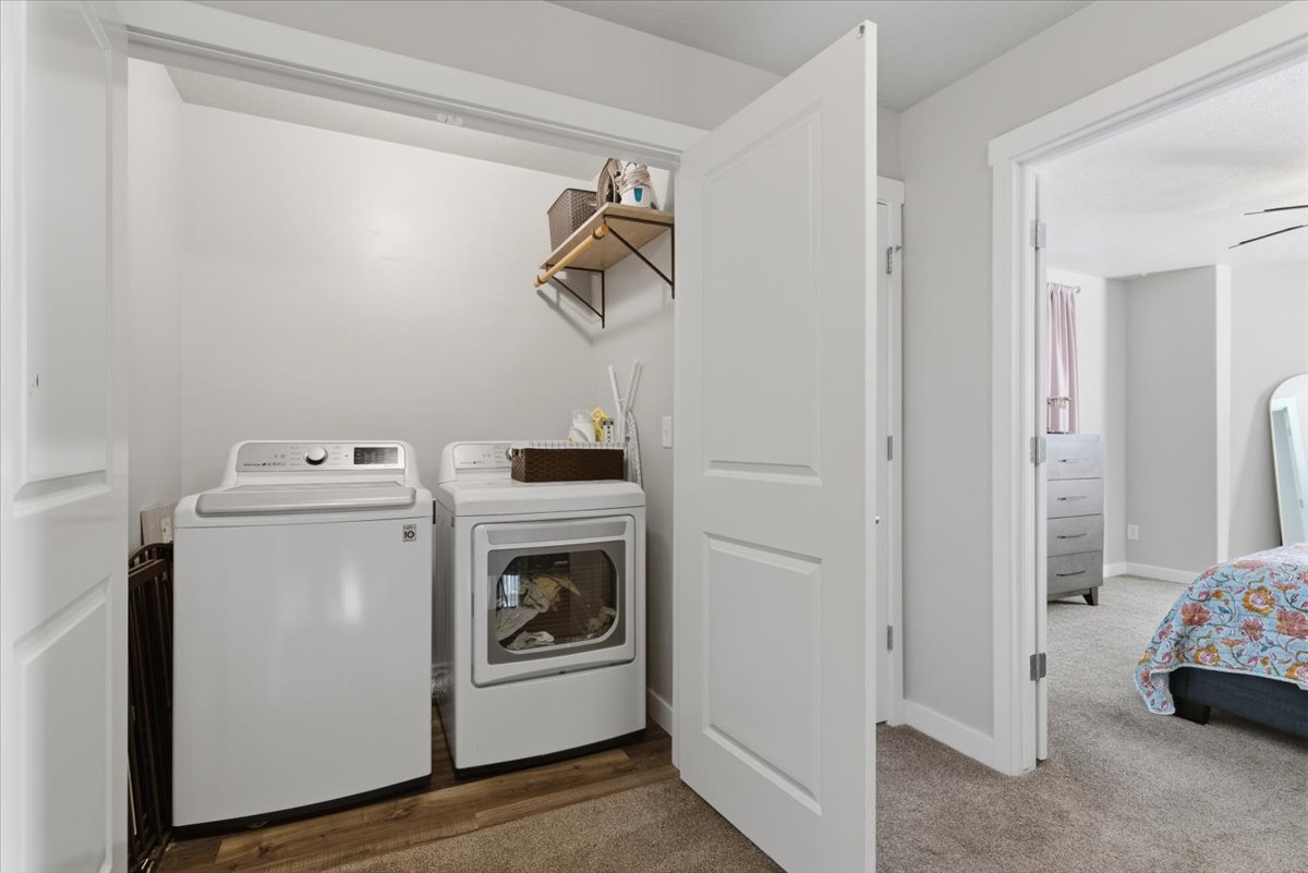 Dedicated laundry closet with wood-finish flooring and an overhead wall shelf