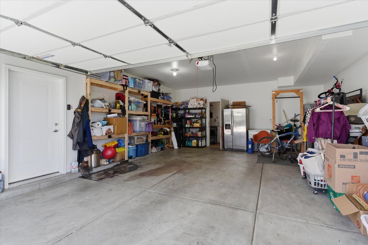 Spacious garage with a concrete floor, built-in shelving, and a pedestrian door