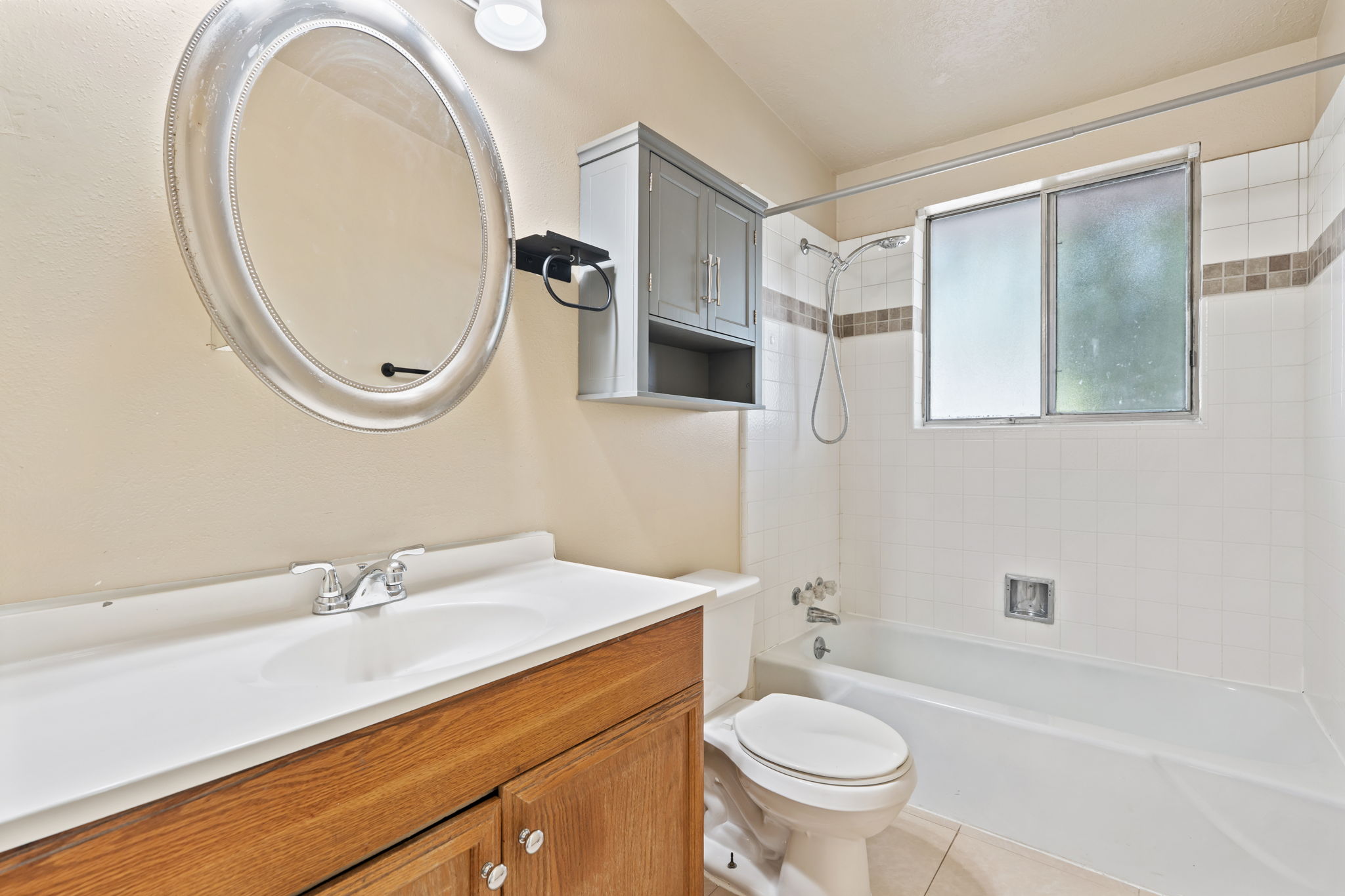 Bathroom featuring a vanity with wood-finish cabinetry, a white countertop, and an oval mirror