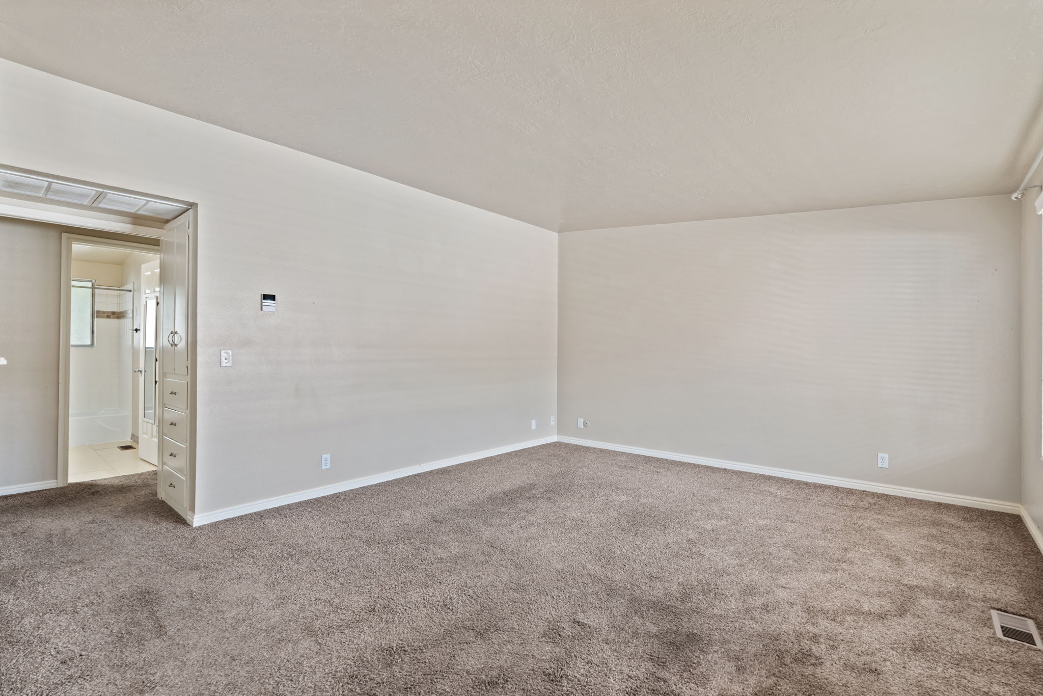 Spacious room featuring neutral carpeting and light-toned walls