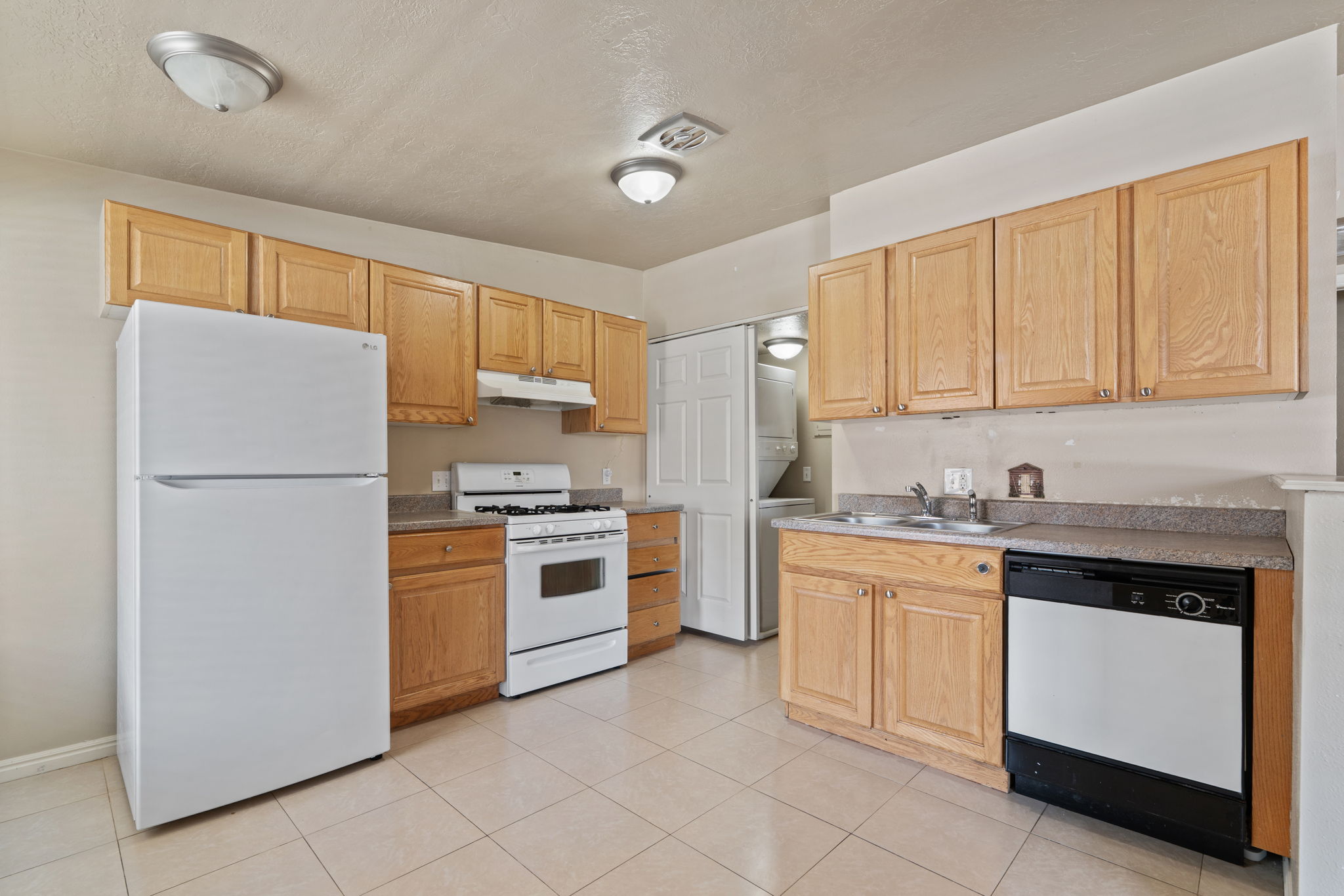 Kitchen featuring wood cabinetry, laminate countertops, and white appliances including a refrigerator, range, and dishwasher