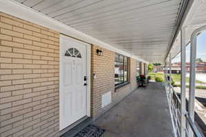 Entry porch featuring a light brick facade, white paneled door with an arched transom, and a concrete walkway