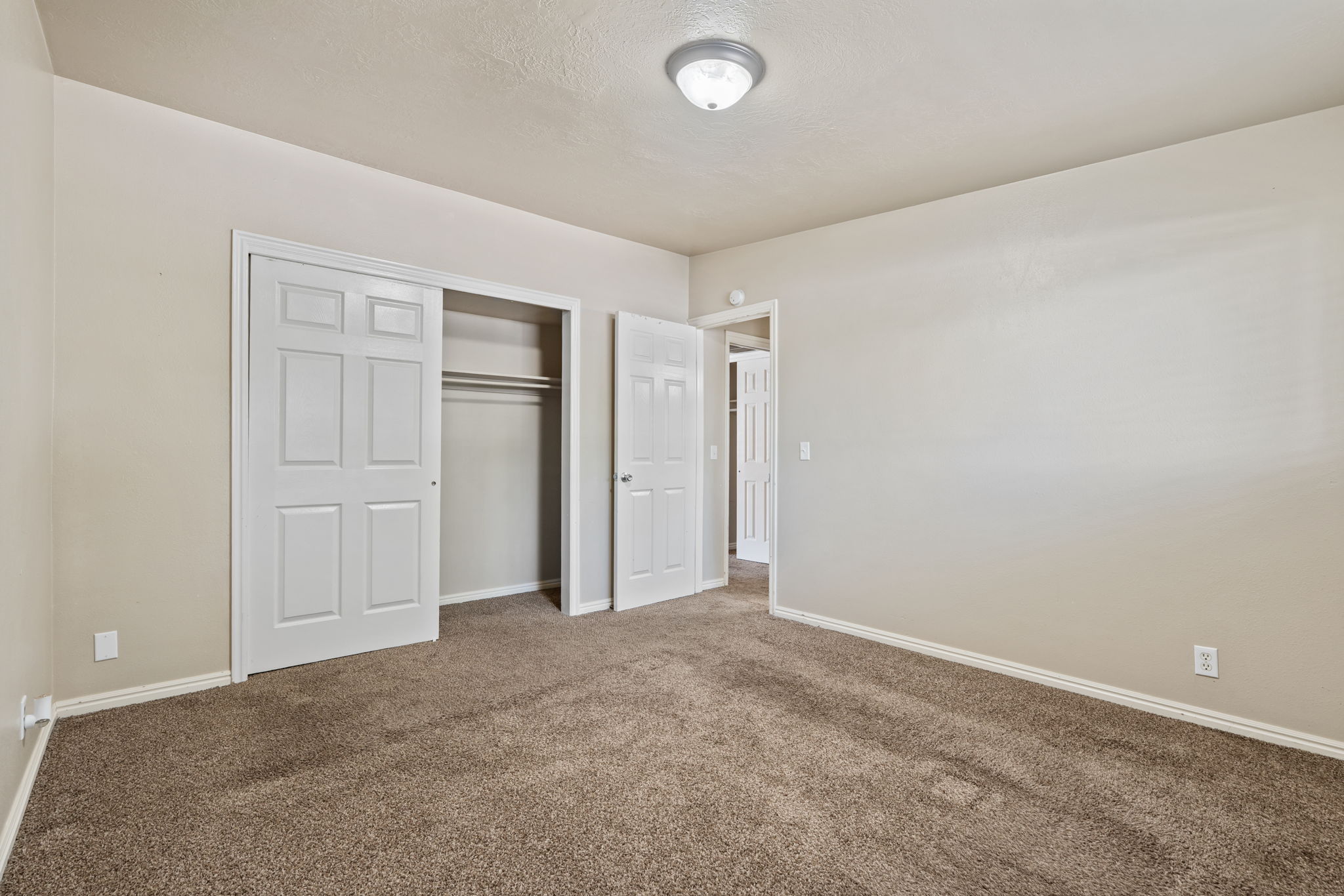 Neutral-toned bedroom featuring wall-to-wall carpeting and white baseboards
