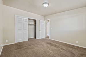 Neutral-toned bedroom featuring wall-to-wall carpeting and white baseboards