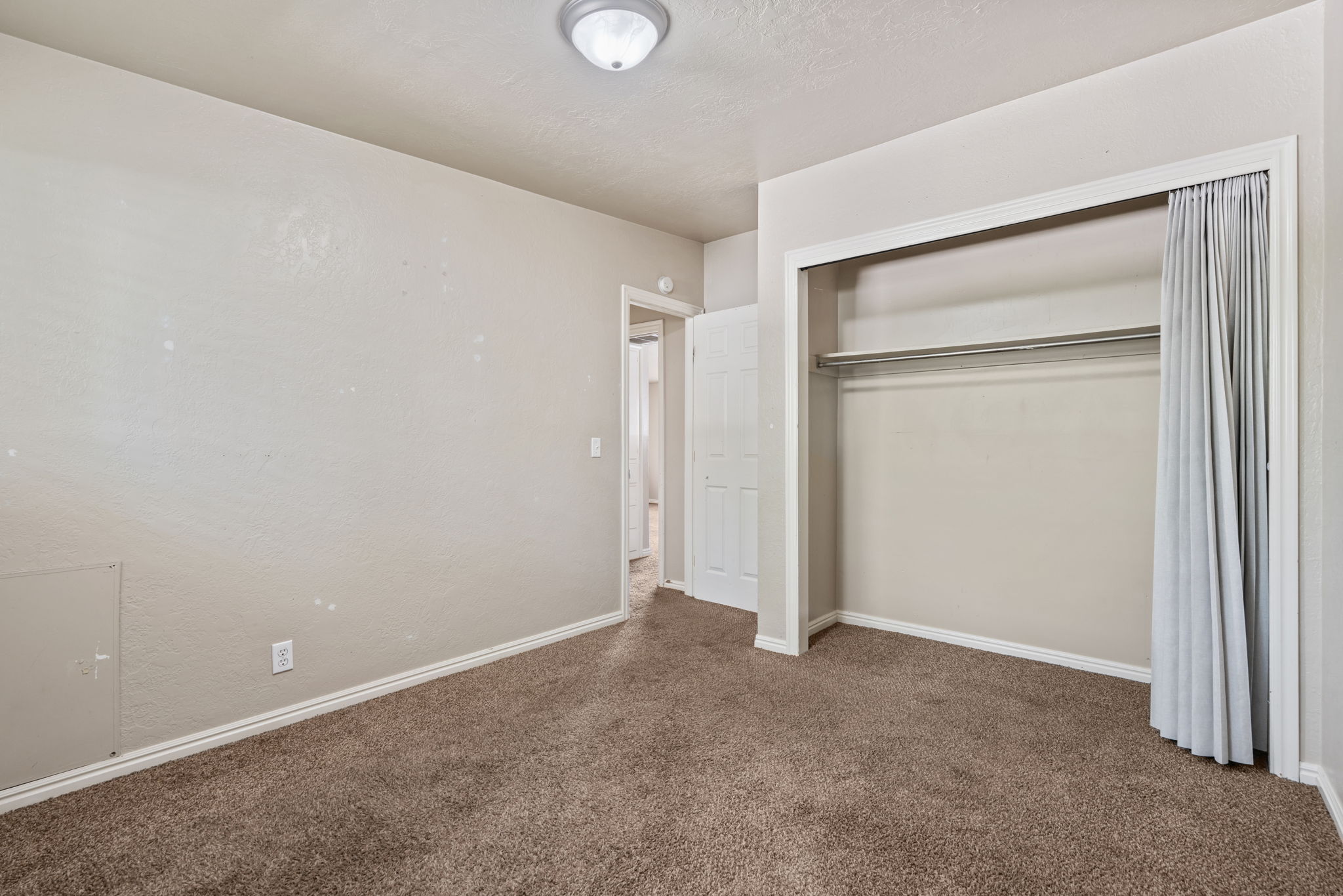 Carpeted room featuring a built-in closet with hanging rod, light-colored walls, and white trim