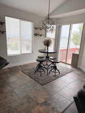 Dining area featuring multi-toned tile flooring, a geometric pendant light fixture, and a sliding glass door providing access to an exterior deck