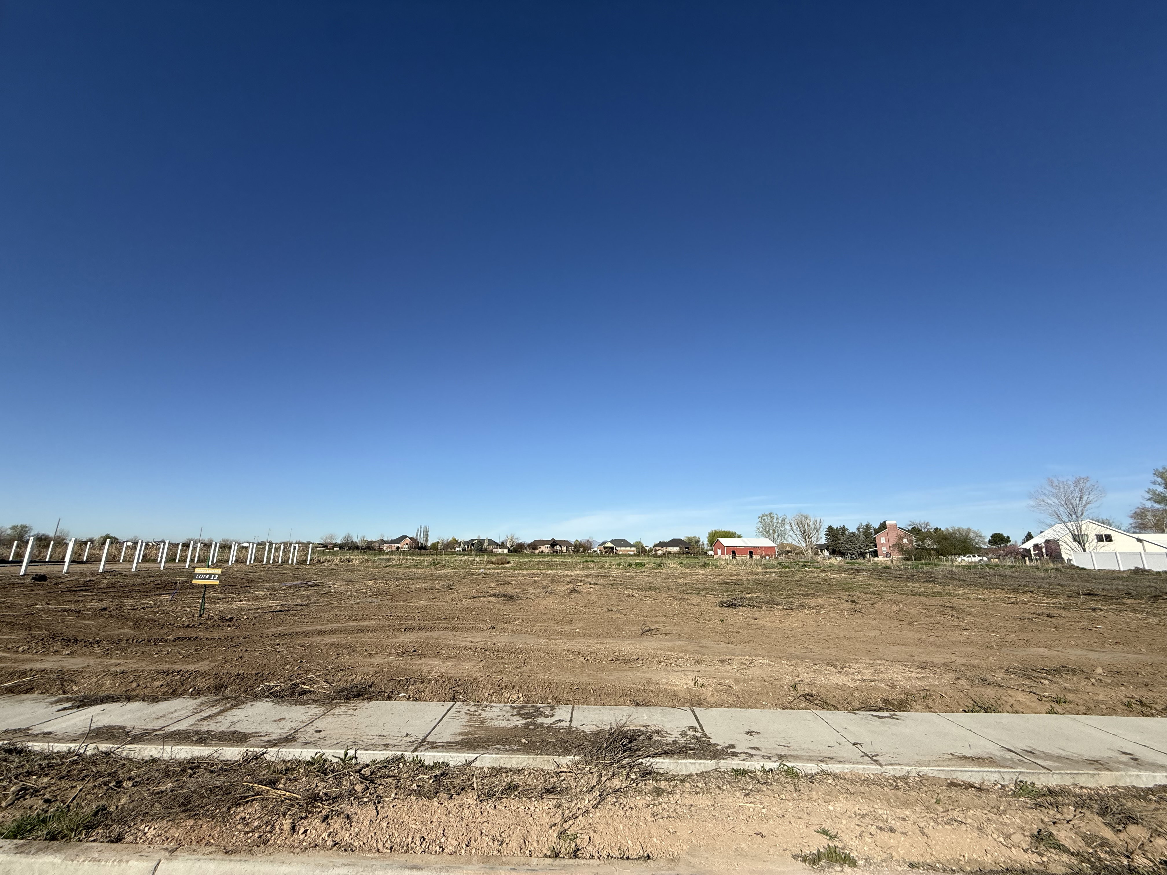 Expansive cleared lot with a newly installed concrete sidewalk and curb