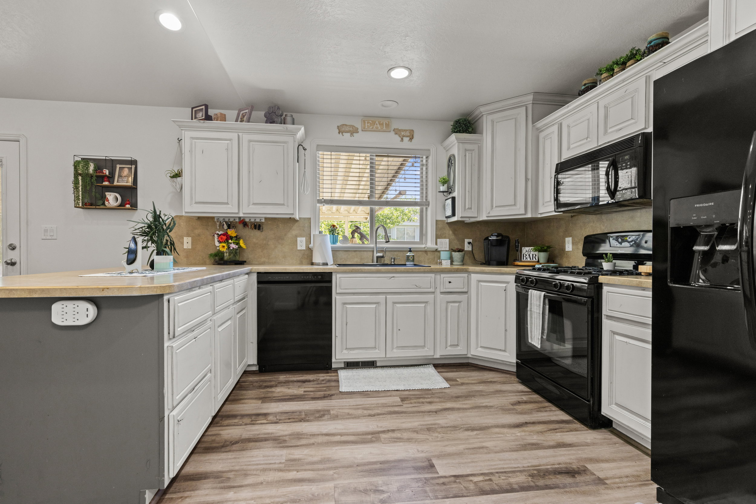 Kitchen featuring wood-finish flooring, white cabinetry, a built-in microwave, a gas range, and a breakfast bar with a light-toned countertop