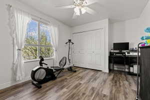 Spacious room featuring wood-finish flooring, a ceiling fan, and a large window with blinds
