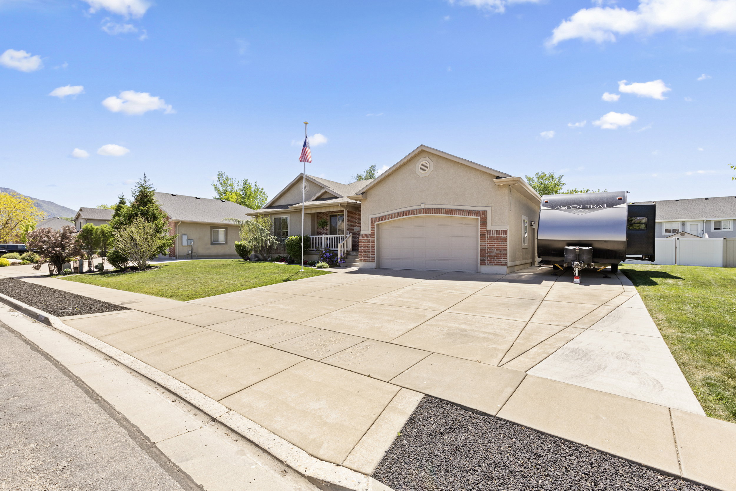 Single-story residence featuring a two-car garage with an arched opening, a brick facade accent, a covered front porch, and a concrete driveway