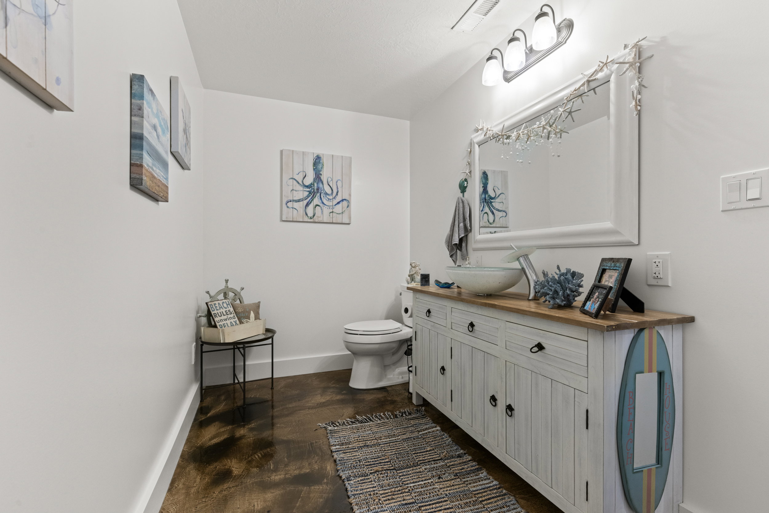 Powder room featuring a distressed white vanity with wood-finish countertop, a vessel sink, and a framed mirror