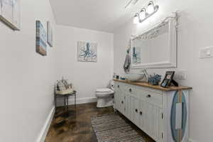 Powder room featuring a distressed white vanity with wood-finish countertop, a vessel sink, and a framed mirror