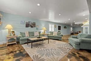 Spacious living area featuring light blue walls, recessed lighting, white window shutters, and unique patterned flooring
