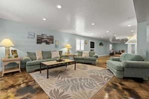 Spacious living area featuring recessed lighting, light blue walls, and a large area rug with a botanical pattern