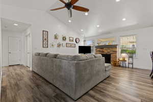 Spacious living area featuring wood-finish flooring, a vaulted ceiling, and recessed lighting
