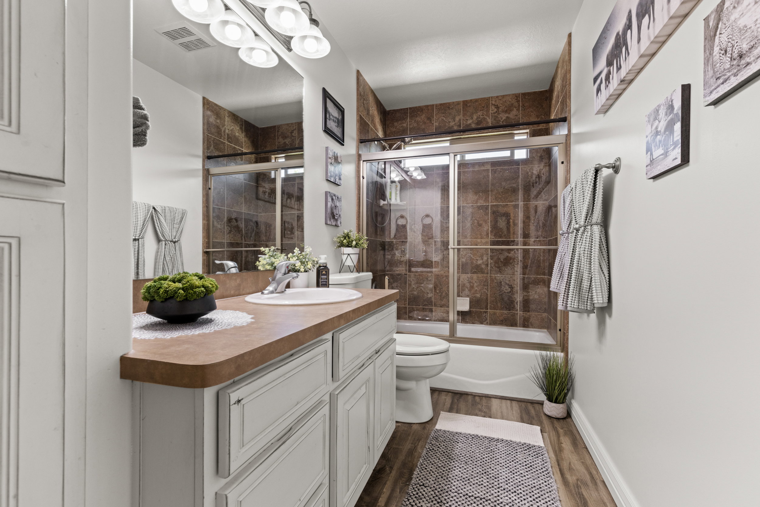 Bathroom featuring a white vanity with paneling, a single basin sink, and a countertop