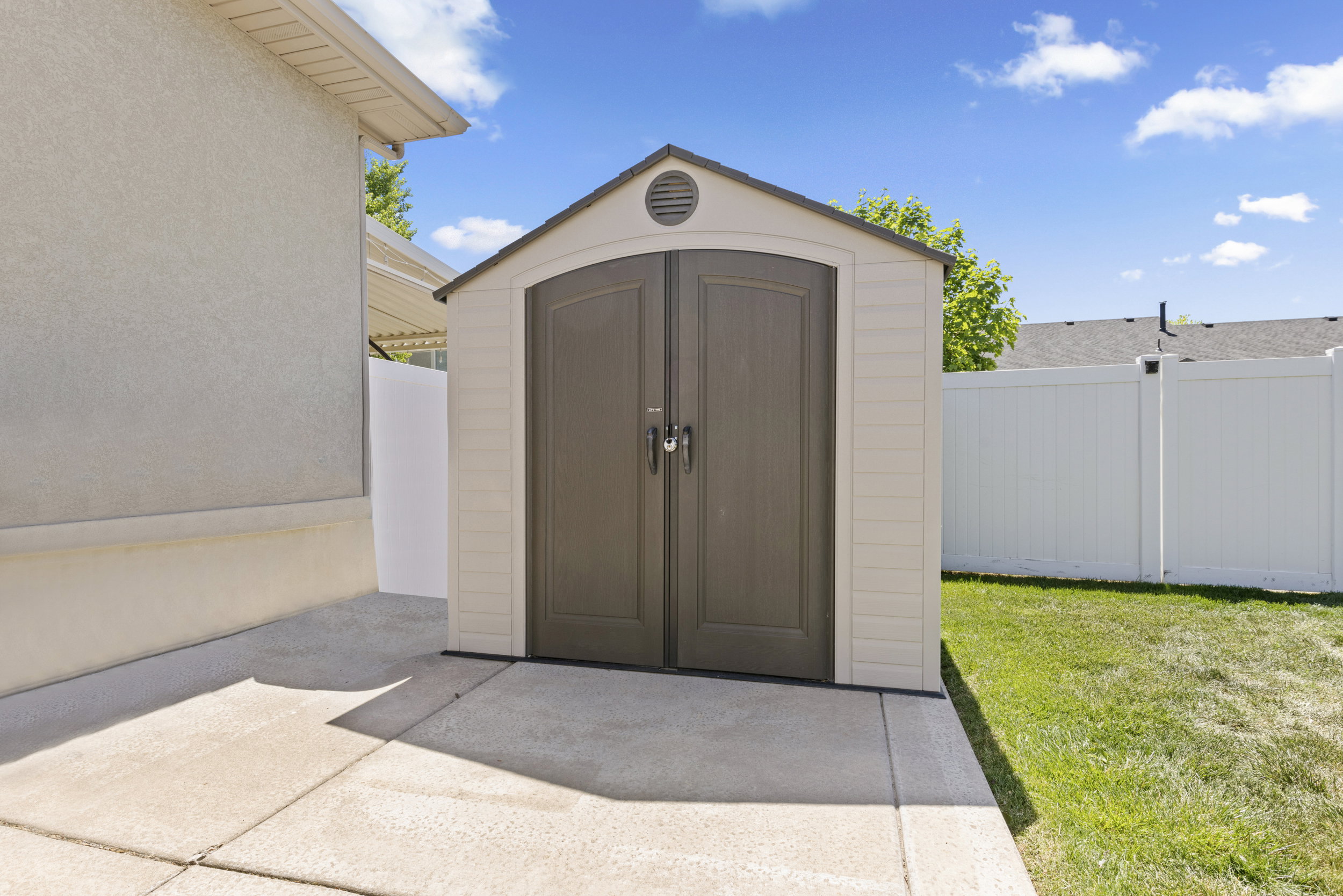 Outdoor storage shed featuring double doors and a gable roof with a circular vent