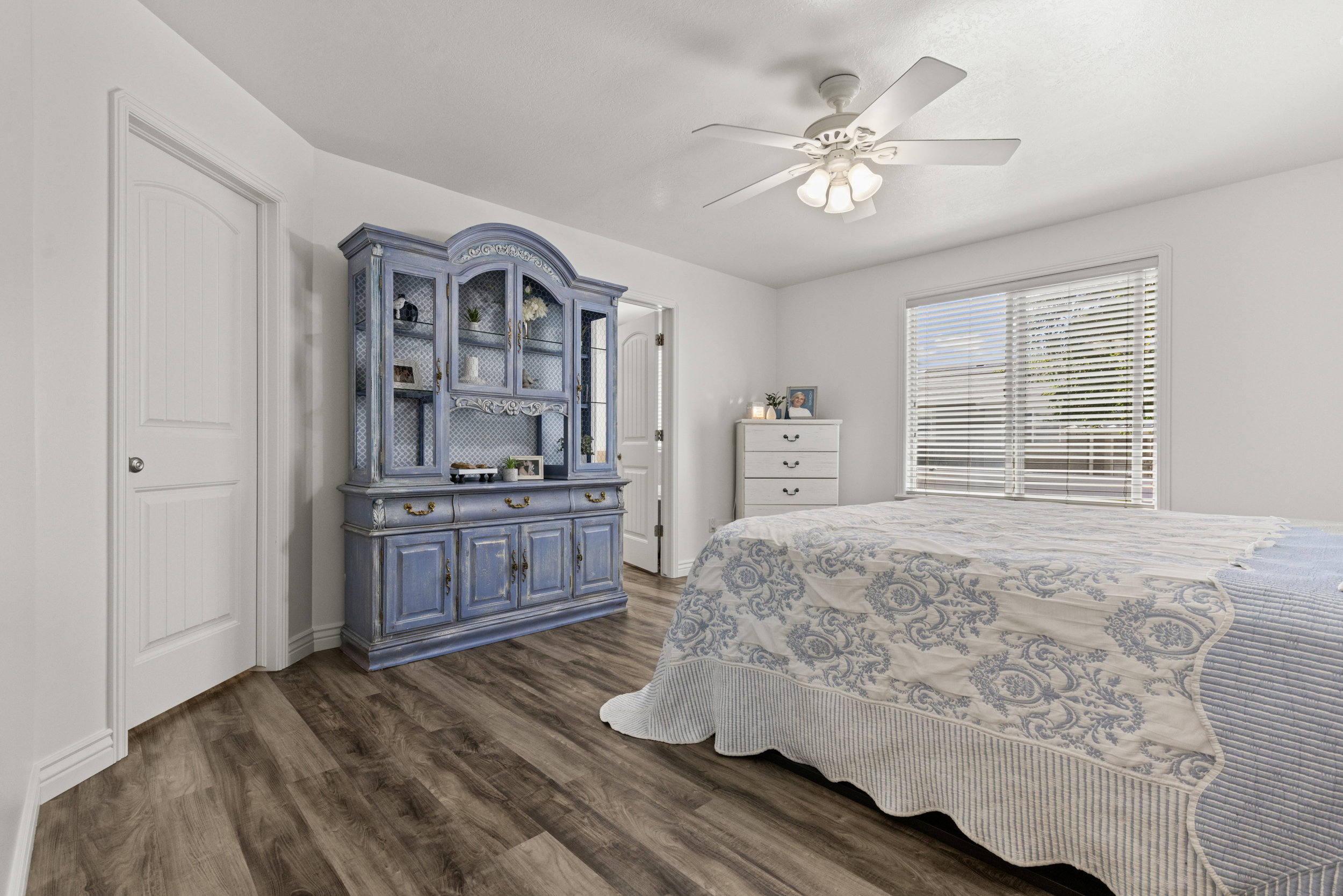 Bedroom featuring wood-finish flooring, white walls, and a ceiling fan with light fixture