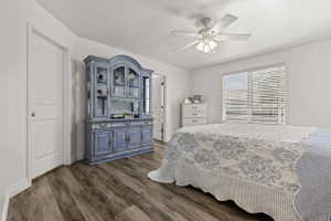 Bedroom featuring wood-finish flooring, white walls, and a ceiling fan with light fixture