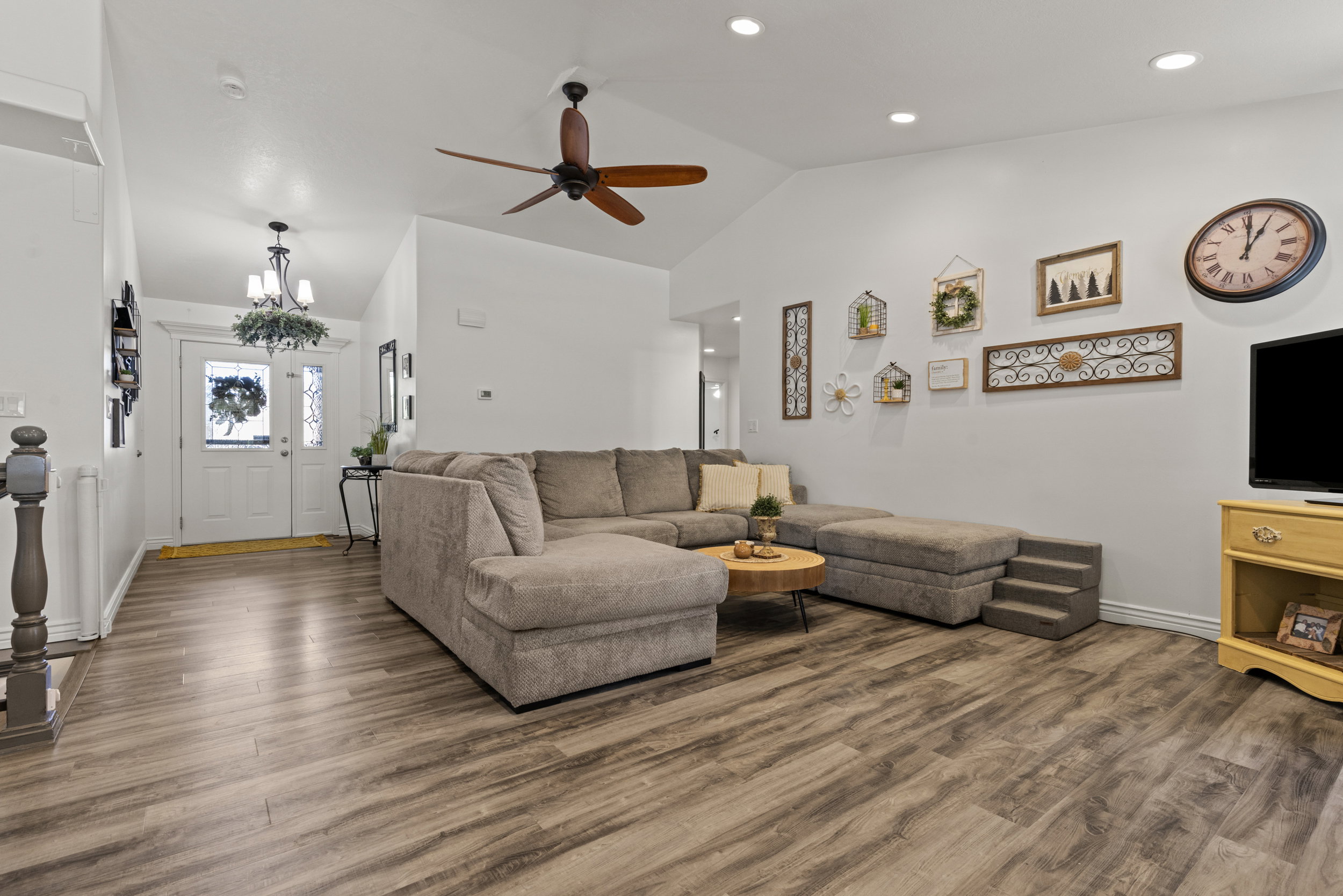 Spacious living area featuring wood-finish flooring, vaulted ceilings, and recessed lighting