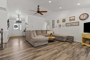 Spacious living area featuring wood-finish flooring, vaulted ceilings, and recessed lighting