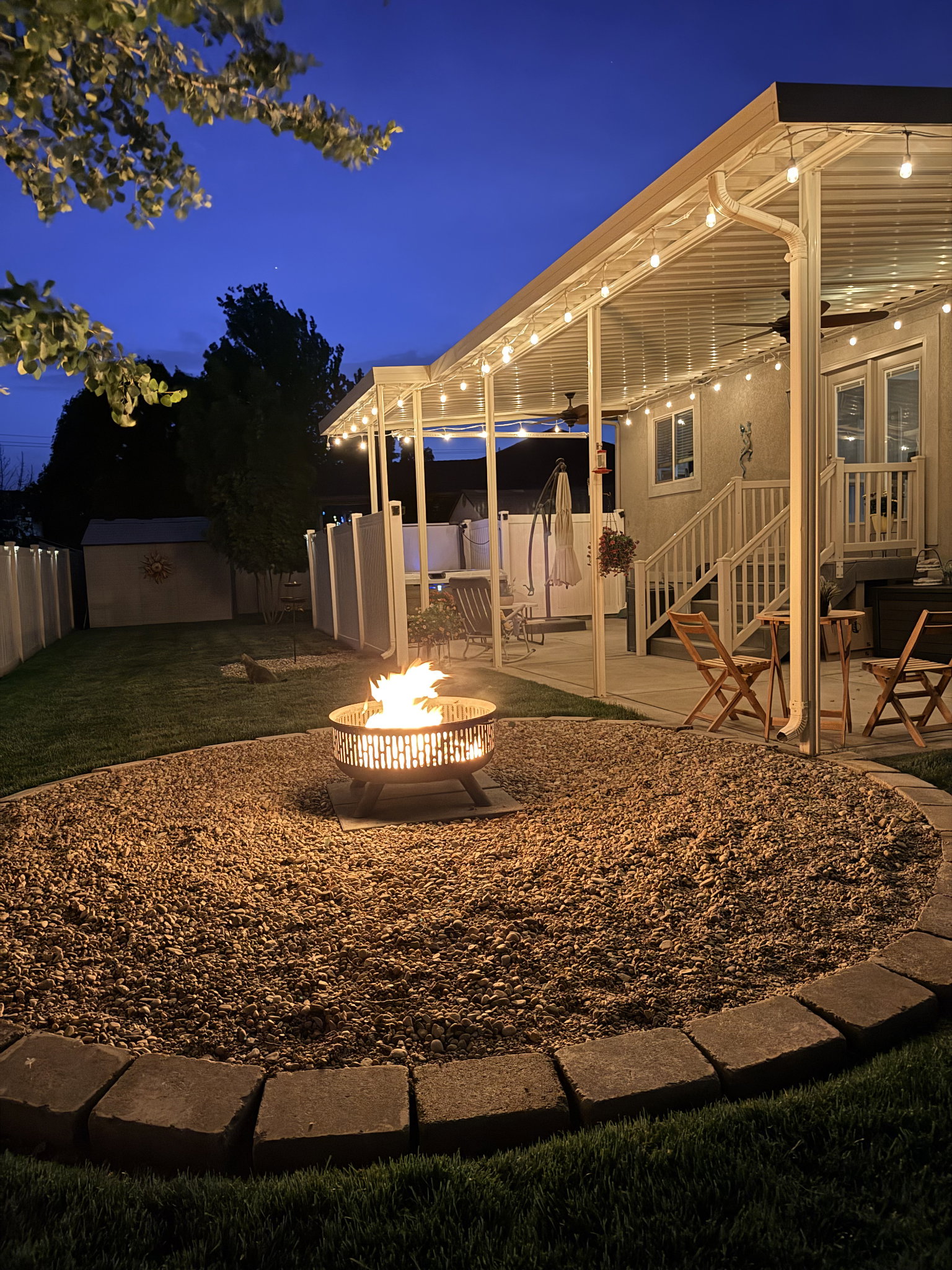 Expansive outdoor covered patio featuring string lighting, an exterior staircase, and a ceiling fan