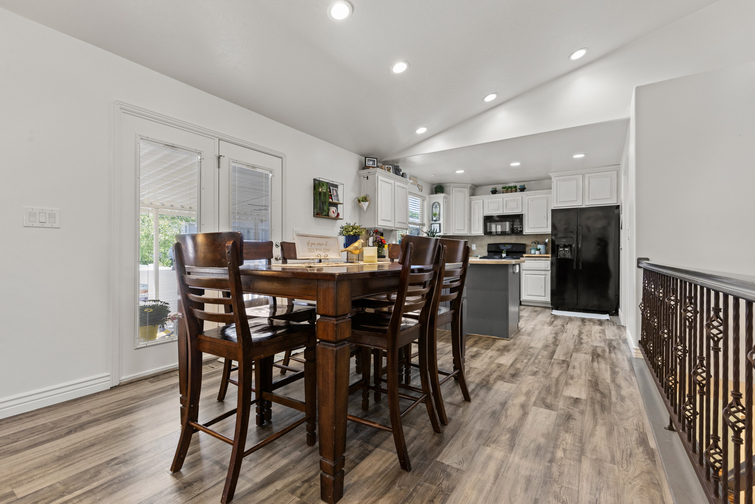 Open-concept space featuring wood-finish flooring, recessed lighting, and a kitchen with white cabinetry and a dark gray island
