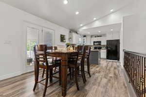 Open-concept space featuring wood-finish flooring, recessed lighting, and a kitchen with white cabinetry and a dark gray island