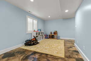 Spacious room featuring light blue walls, white trim, recessed lighting, and a window with white plantation shutters
