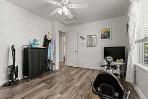 Spacious room featuring wood-finish flooring, white baseboards, and a white ceiling fan