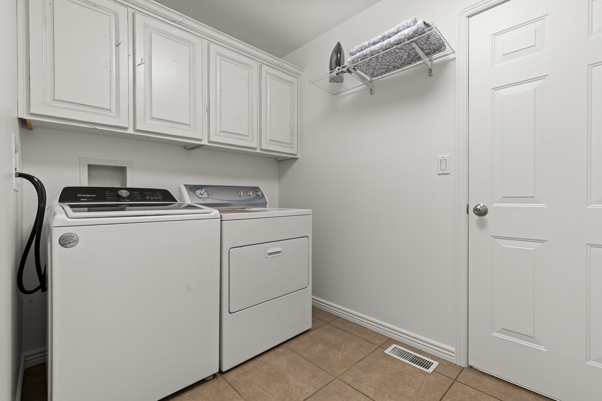 Laundry area featuring upper cabinetry, a paneled door, and tile flooring