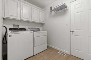 Laundry area featuring upper cabinetry, a paneled door, and tile flooring