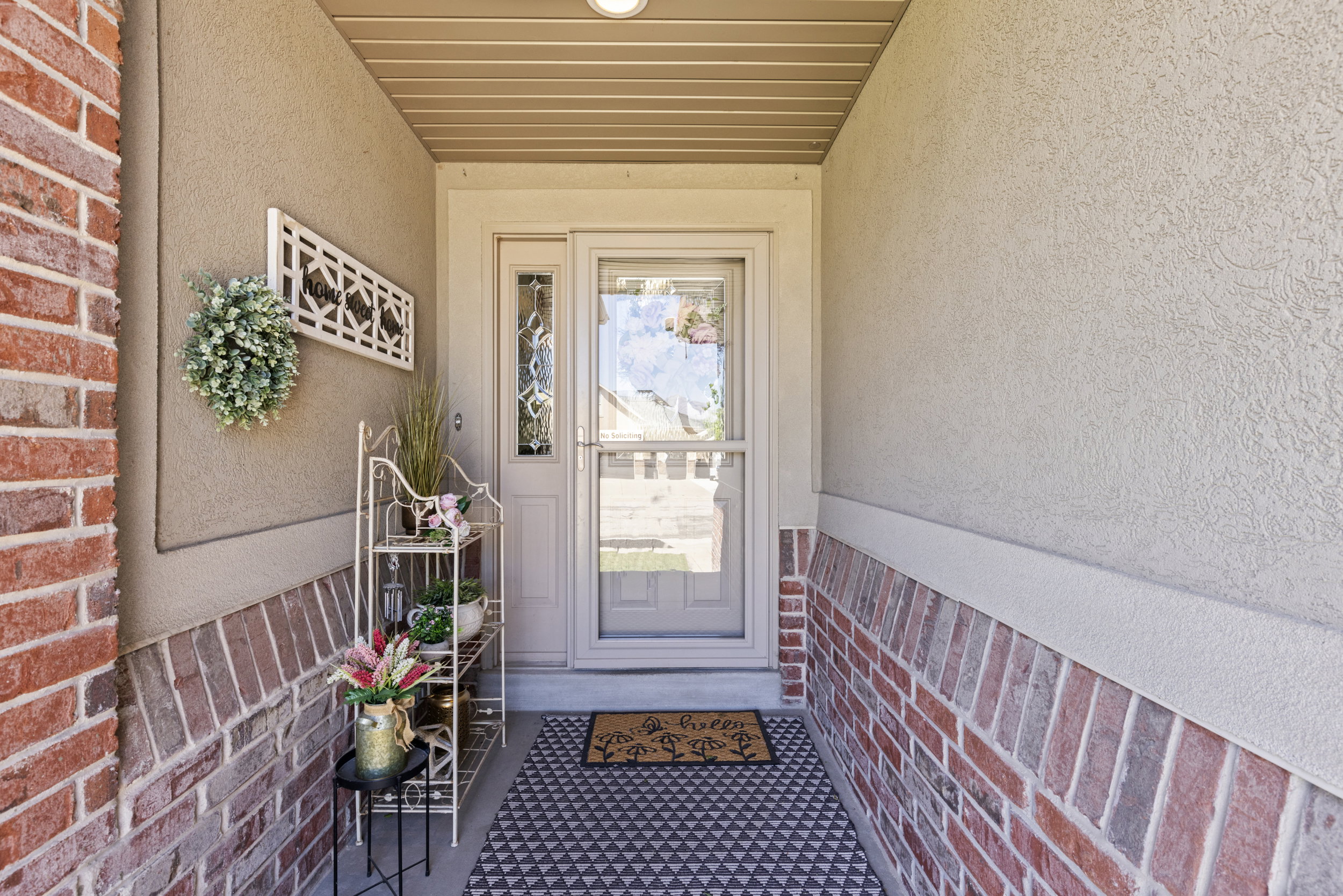 Covered entry featuring a traditional front door with a decorative glass sidelight and a full-view storm door