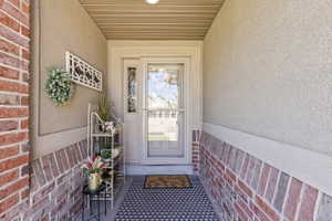 Covered entry featuring a traditional front door with a decorative glass sidelight and a full-view storm door