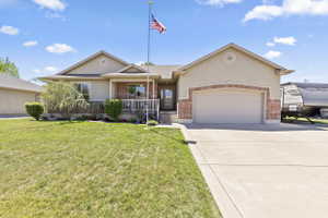 Single-story residence featuring a stucco exterior with brick accents, an attached garage, a covered front porch with white railings, and a concrete driveway