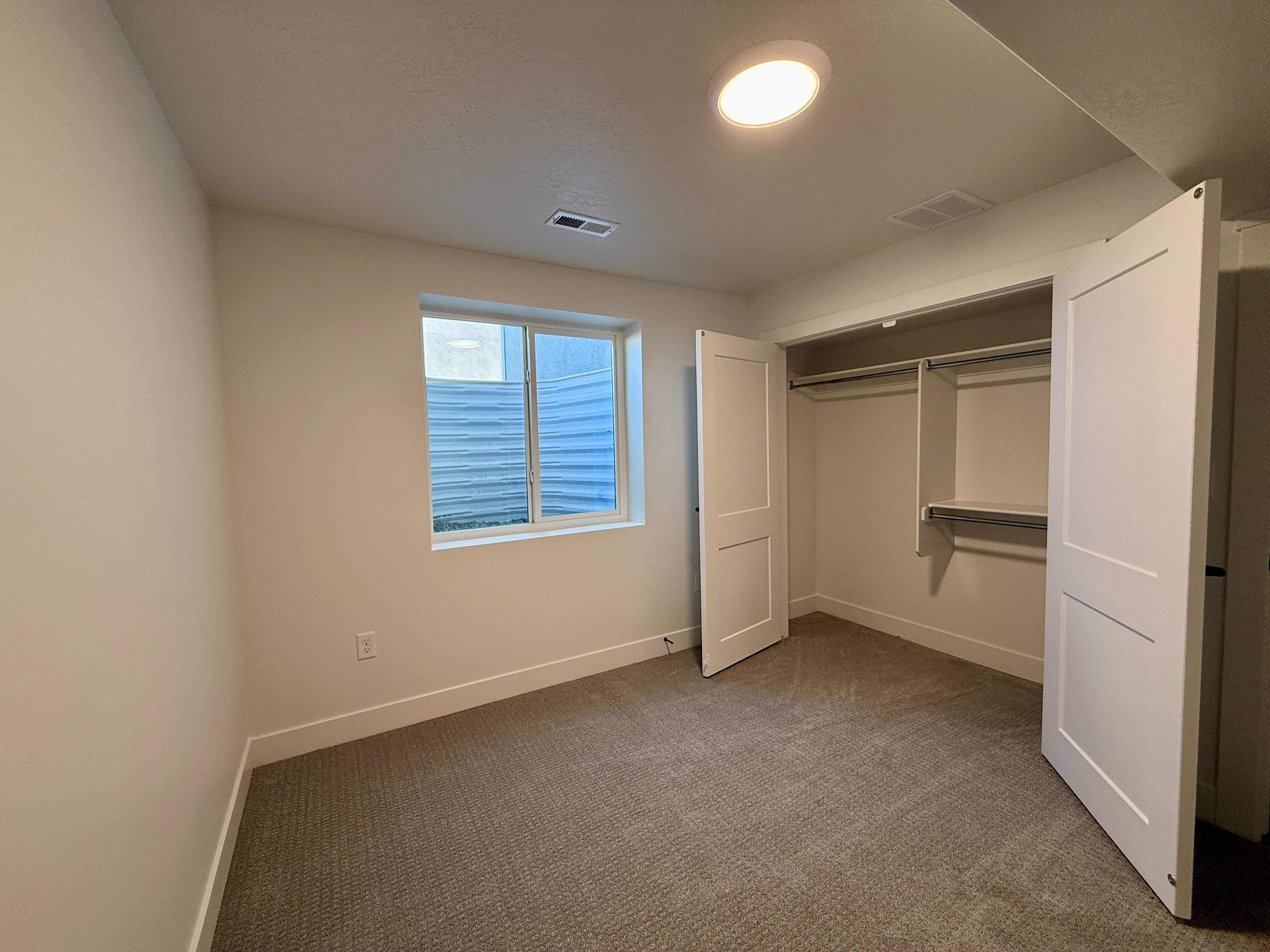 Carpeted room featuring a double-panel window, recessed lighting, and a closet with bifold doors and built-in shelving