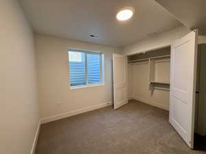 Carpeted room featuring a double-panel window, recessed lighting, and a closet with bifold doors and built-in shelving