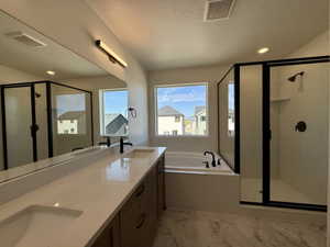 Contemporary bathroom featuring a double vanity with stone countertops, a soaking tub with a black faucet, and a glass-enclosed shower with black framing