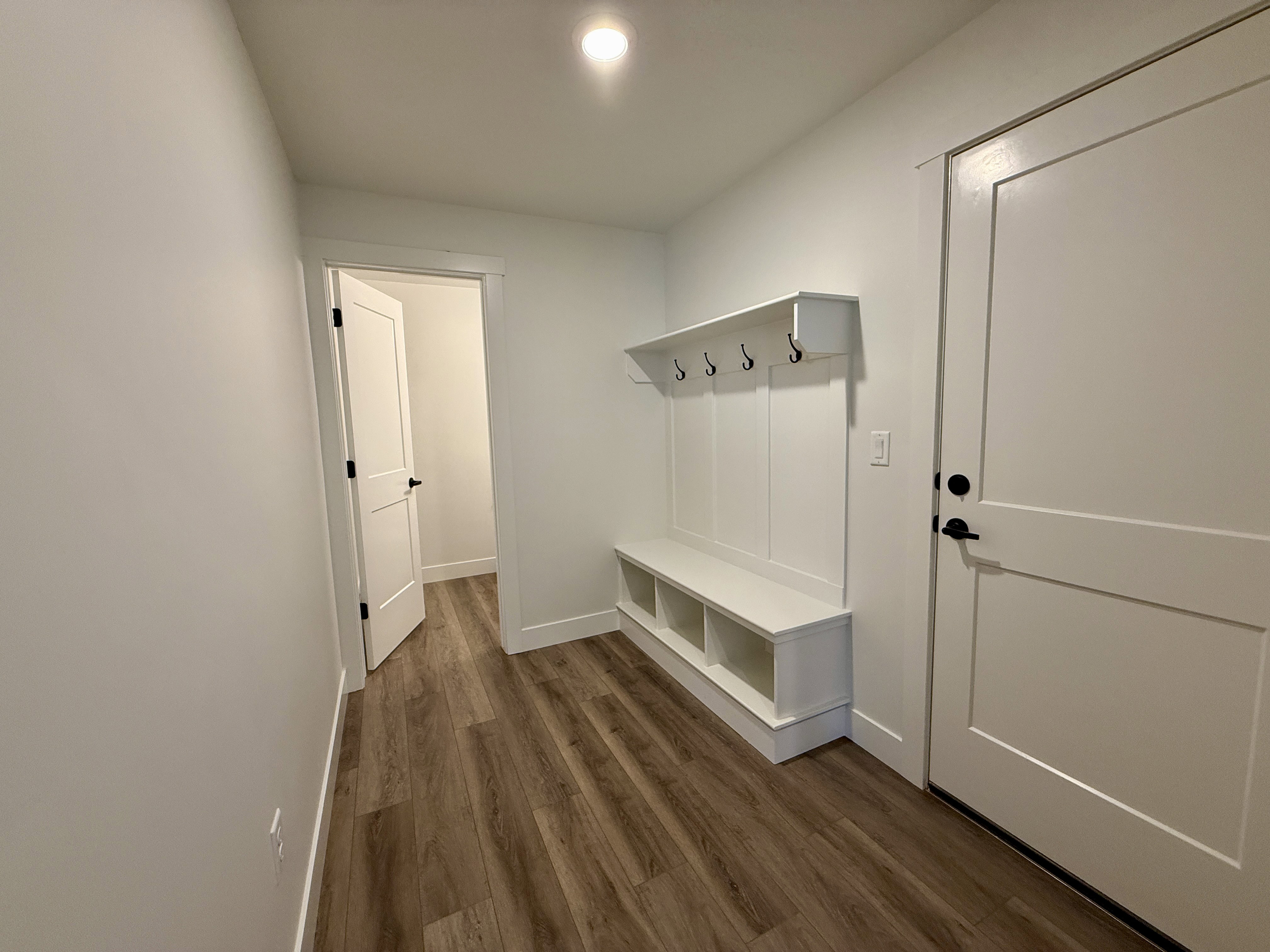 Entryway featuring a built-in bench with cubby storage, paneling, and coat hooks