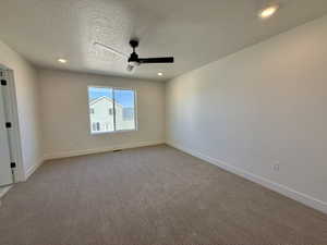 Spacious room featuring neutral carpeting, a large window, a ceiling fan with integrated lighting, and recessed ceiling lights