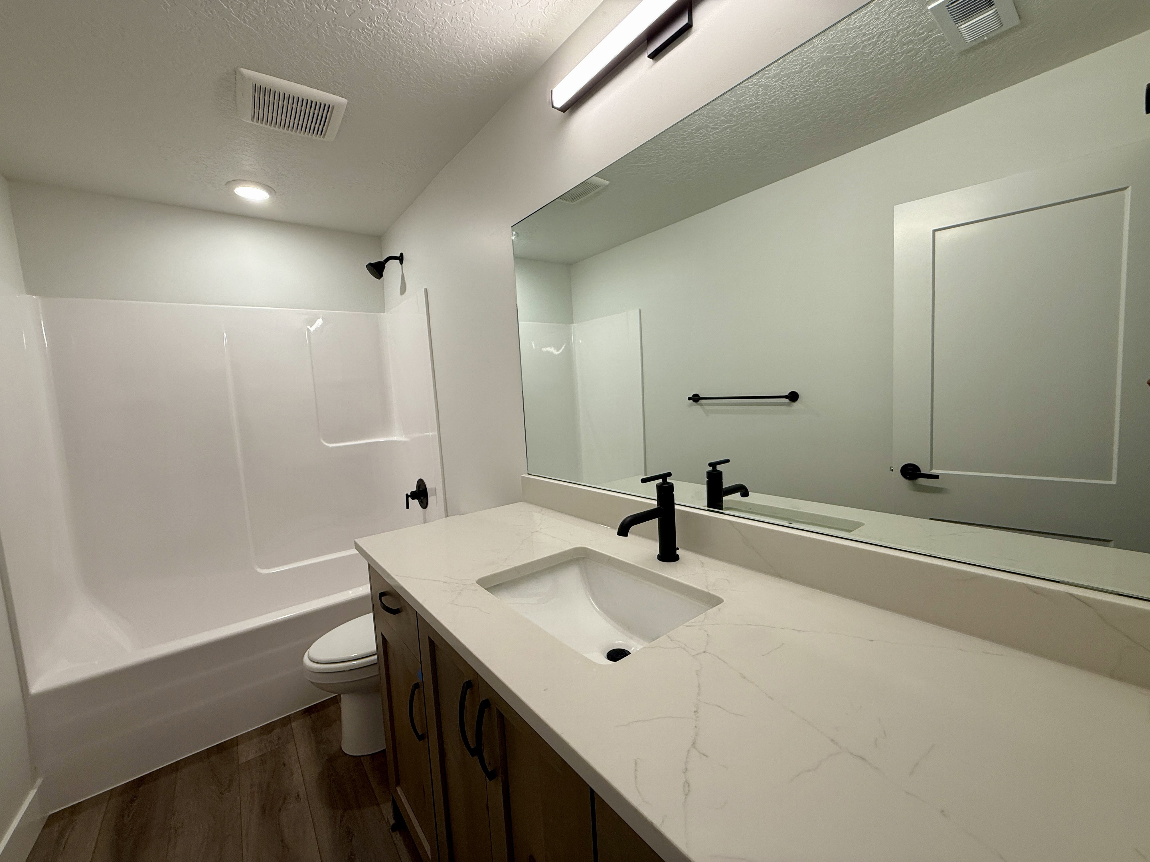 Bathroom vanity featuring a light-toned countertop with an integrated sink and matte black fixtures