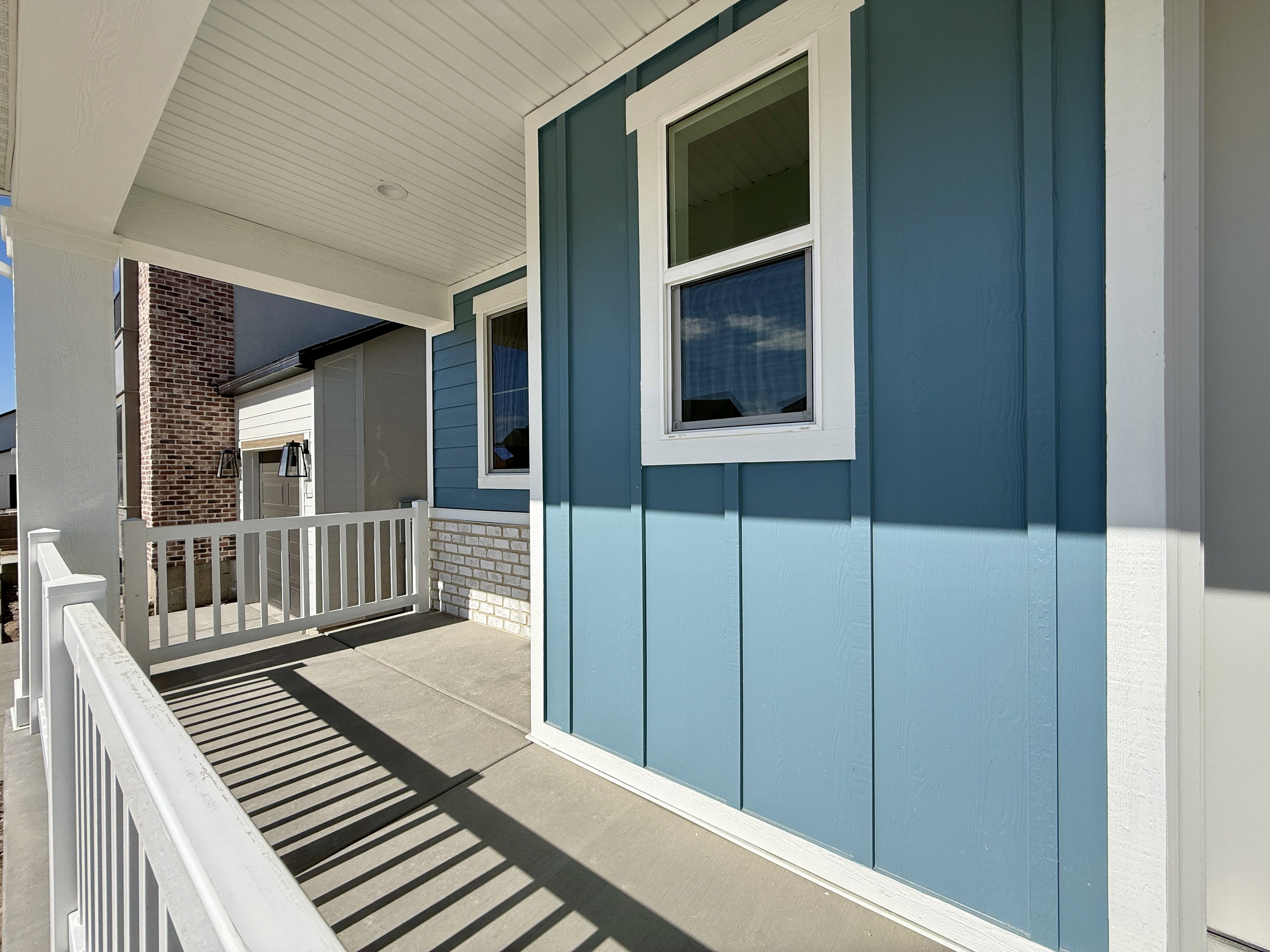 Covered front porch featuring white railings, a concrete surface, and a beadboard ceiling