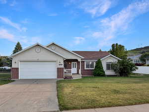 Ranch-style exterior featuring a two-car garage, brick accents, stucco siding, and a covered entry