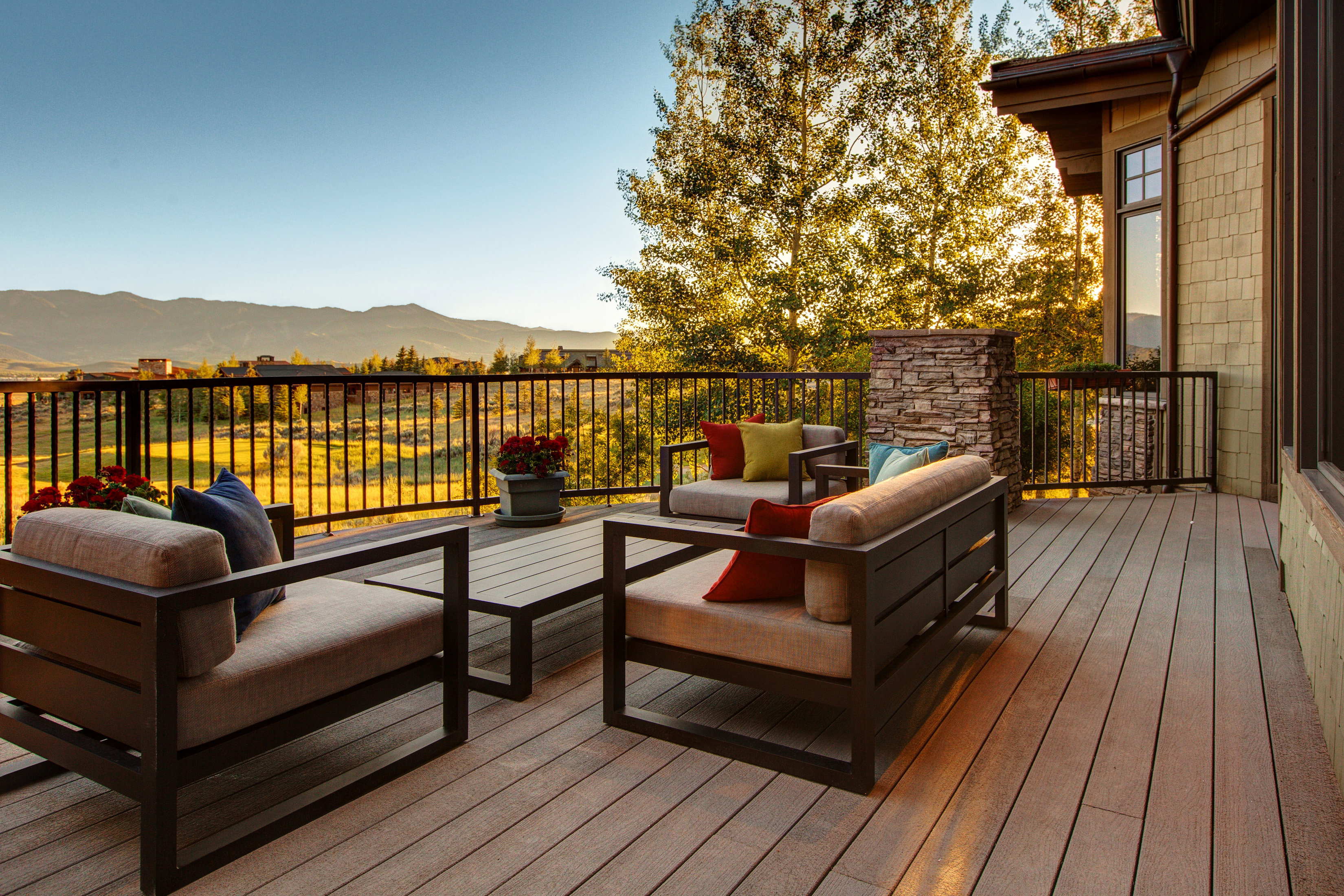 Spacious outdoor deck featuring composite decking, a stone-clad pillar, and a black metal railing